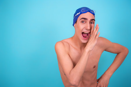 Portrait of a young man in a swimming cap on a blue backgroundの写真素材