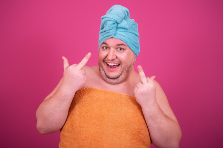 Portrait of happy man with towel on head isolated on pink backgroundの写真素材