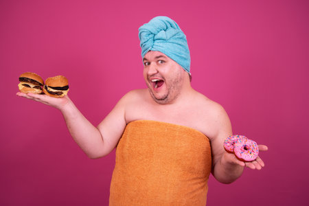 Cheerful fat man with donuts and towel on his headの写真素材