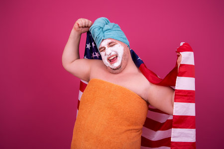 Funny man with a towel on his head and a turban on his head is holding the American flag.の写真素材