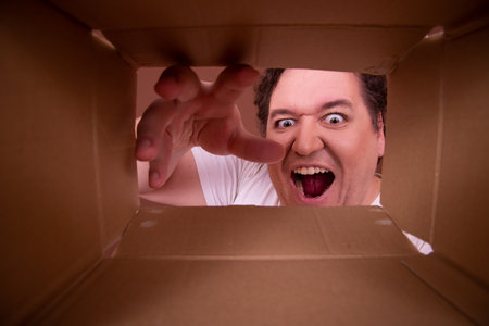 Surprised young man opening cardton box and looking inside.の写真素材