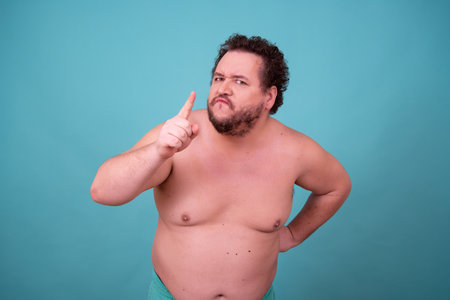 Fat man with overweight in a towel on a turquoise backgroundの写真素材