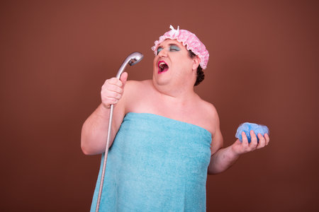 Portrait of fat overweight man wearing pink shower cap against brown backgroundの写真素材