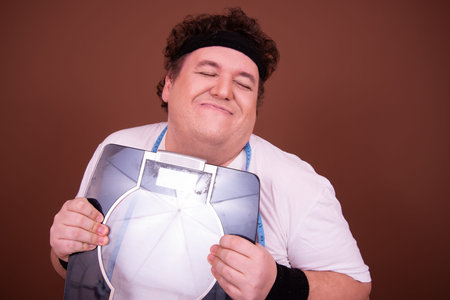 Portrait of fat overweight man against brown backgrounnd