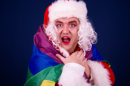 Portrait of a man dressed as Santa Claus against a blue backgroundの写真素材