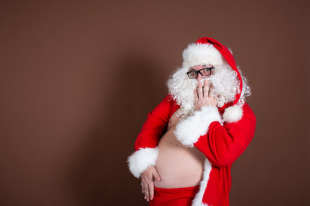 Portrait of a happy Santa Claus in red clothes over brown backgroundの写真素材