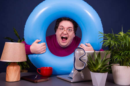 Funny man with a blue inflatable ring in the office.