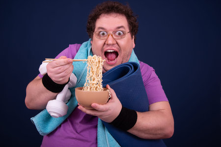 Portrait of a fat man eating noodles on a blue background.
