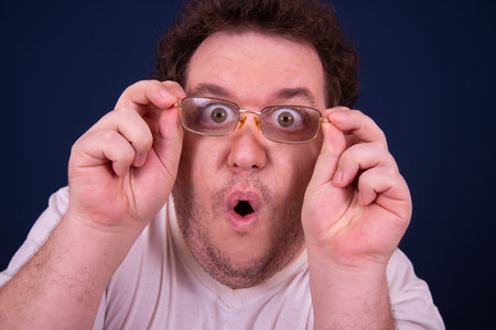 Surprised man with glasses on blue background. Studio shot.の写真素材