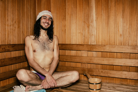 An attractive guy with long hair is relaxing in the sauna. Relaxation and pleasure.の写真素材