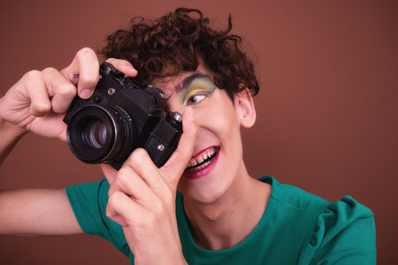 Young beautiful woman with curly hair and professional photo camera in her handsの写真素材