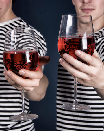 Man and woman holding glasses of red wine on a dark blue backgroundの写真素材
