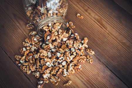 Walnut kernels and whole walnuts on rustic old wooden table glass jarの写真素材