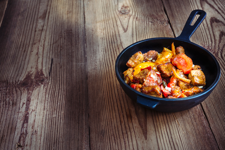 roasted pork with sweet pepper and tomatoes, basil and garlic wood backgroundの写真素材