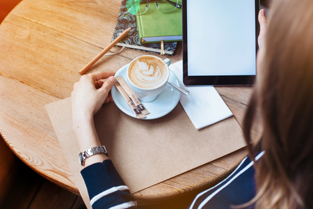 Close up of womens hands holding digital tablet with blank copy space screen for your advertising text Female reading news on modern tablet during rest in cafe. View from above.Focus on tablet.の写真素材