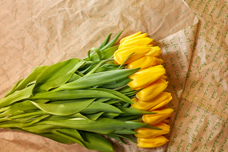 Fresh flower composition, bouquet yellow tulips on craft paper background. Valentine, Womens, 8 march, birthday, mothers day present. Copy space, close up, top view.の写真素材