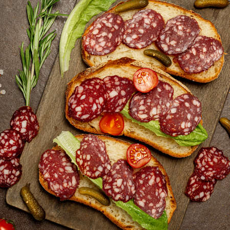 Toast with dried sausage lettuce on a dark wooden background, rustic style.の写真素材
