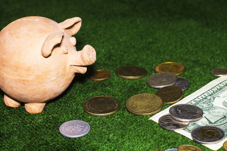 Tax day. Piggy bank with a dollar note and coins against the green carpet background.の写真素材