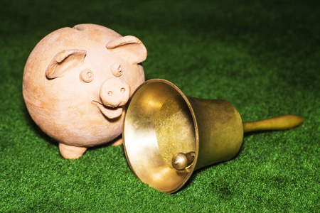 Tax day. Piggy bank with a bell against the green carpet background.の写真素材