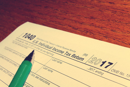 Tax day. The tax form 1040 and green pen is on a wooden table.の写真素材