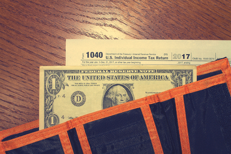 Tax day. The tax form 1040, dollar and orange black wallet is on a wooden table.の写真素材