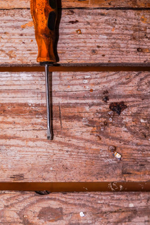 The screwdriver lies on an old wooden table in the workshop. Image contains copy space.