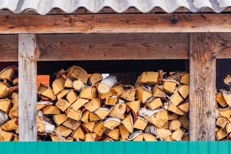 A lot of chopped firewood lies in a woodpile as fuel for a stove or fireplace. Rural life or forest industry.の写真素材