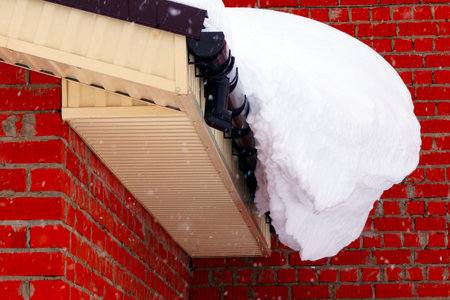 A lot of snow lies on a residential building and large snowdrifts around. Seasons.
