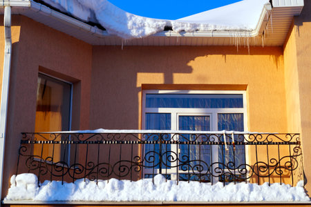A lot of snow lies on a residential building and large snowdrifts around. Seasons.の写真素材