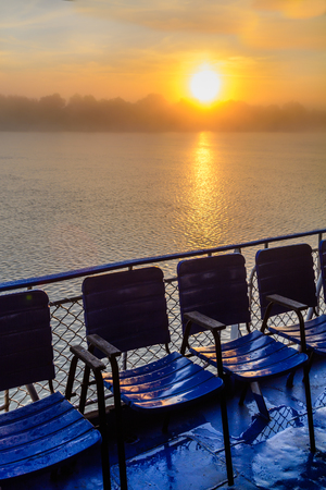 Landscape of sunset from an observation platform with chairs. Beautiful view of colorful sunset on the peaceful sea.の写真素材