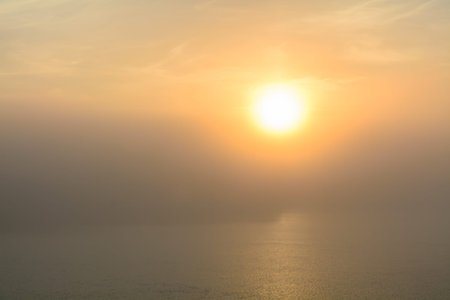Sunset view from the deck of a boat. Horizontal view of a foggy sun-setting background from the deck of a boat, early in the evening.の写真素材