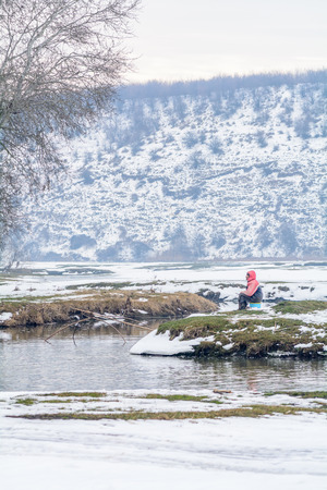 Calugareni, Romania - January 15: Calugareni lake on January 15, 2016 in Calugareni Giurgiu. Vertical winter picture of man fishing in icy water, winter snow background.のeditorial素材