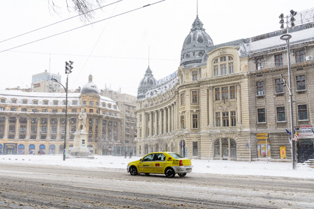 Bucharest, Romania - January 17: University Square on January 17, 2016 in Bucharest, Romania. Bucharest downtown after massive snowing, University Square, city center neighborhood, taxi car street.のeditorial素材