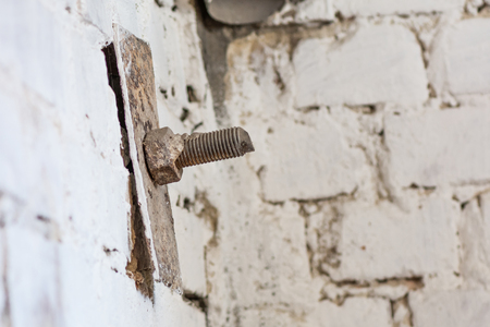 Old screw head in brick. Realistic image with old rusty screw head, bolt, wheel screw isolated on brick wall background.の写真素材