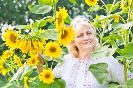 Gardening in summer - happy woman with sunflowers in her gardenの写真素材