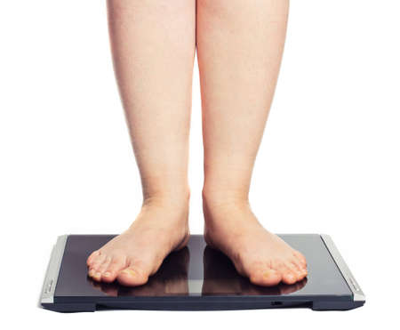 Bare female feet standing on bathroom scale. Isolated on whiteの写真素材