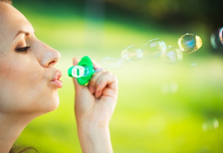 Close-up portrait of a girl blowing soap bubbles in the parkの写真素材