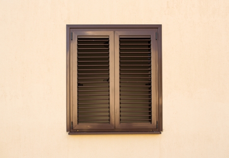 Detail of a window with shutters closed on yellow wallの写真素材