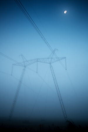 Power lines and pylons in fog in the early morningの写真素材