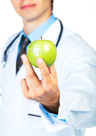 Doctor's hand holding a fresh green apple close-up on white backgroundの写真素材