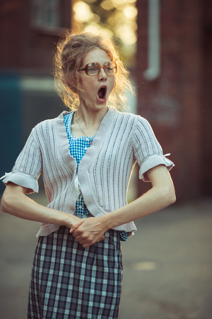 Funny crazy girl student in glasses and a vintage dress talking with his mouth wide open outdoorsの写真素材