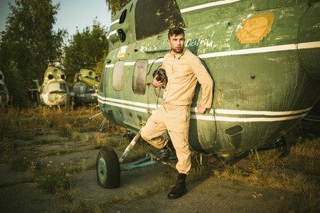 Young serious pilot posing near the helicopterの写真素材