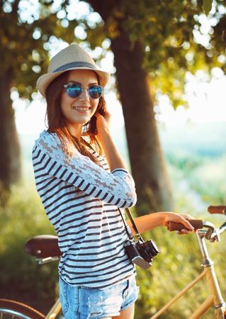 Lovely young woman in a hat riding a bicycle in a park. Active people. Outdoorsの写真素材