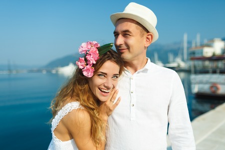 Attractive young couple walking alongside the marina on a luxury waterfront in summer sunshineの写真素材