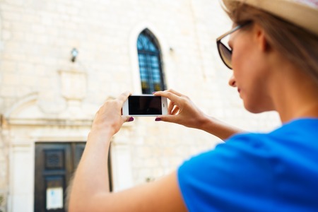 Girl in hat making photos of a church by the smartphone, Montenegro, Balkansの写真素材
