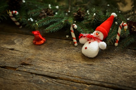 Christmas tree branches with christmas decorations and snowman on wooden texture. Winter holidays backgroundの写真素材