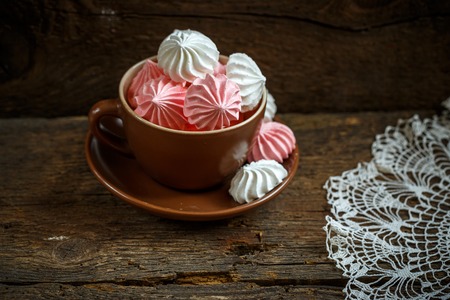 Meringues in a cup on old shabby wooden backgroundの写真素材