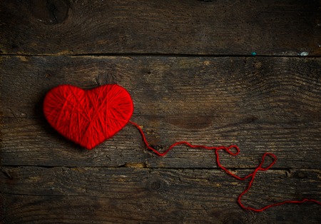Red heart shape made from wool on old shabby wooden background. Image of Valentines dayの写真素材