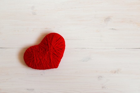 Red heart shape made from wool on white wooden background. Image of Valentines dayの写真素材