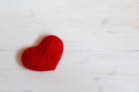 Red heart shape made from wool on white wooden background. Image of Valentines dayの写真素材